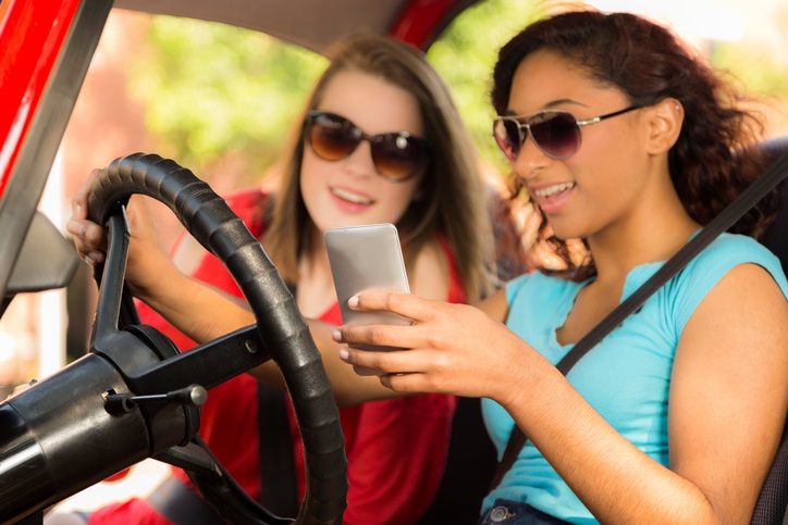 two girls looking at a phone inside a car