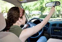 woman adjusting rear mirror in car
