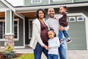 Pregnant Family Standing in Front of a Home